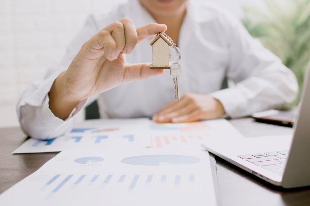 pexels-photo-4161619 Real estate professional presenting a house model with keys, symbolizing property investment and ownership.
